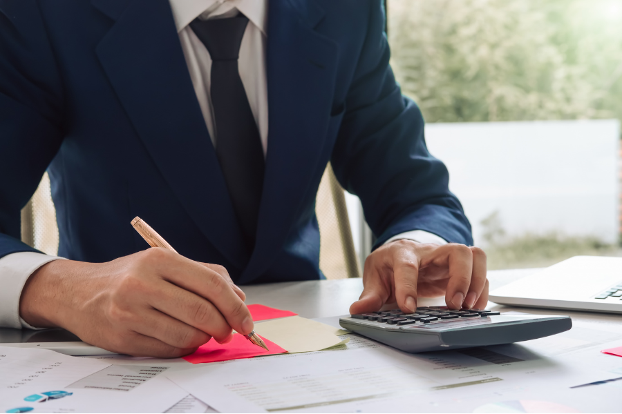 Finance professional calculating business expenses while reviewing financial documents and reports