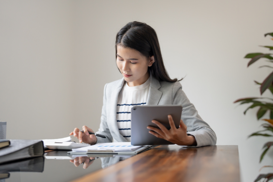 Business professional reviewing financial reports and data on a tablet at an office desk